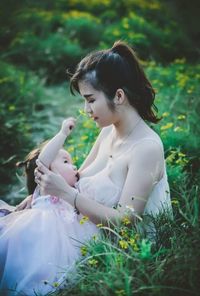 Young woman sitting on grass in field