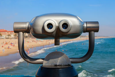 Close-up of coin-operated binoculars by sea against clear sky