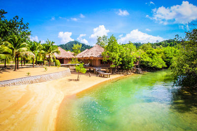 Scenic view of houses at beach amidst trees against blue sky