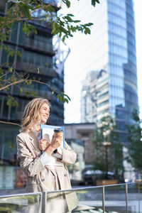 Portrait of young woman standing against buildings