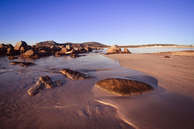 Rocks on beach against clear sky