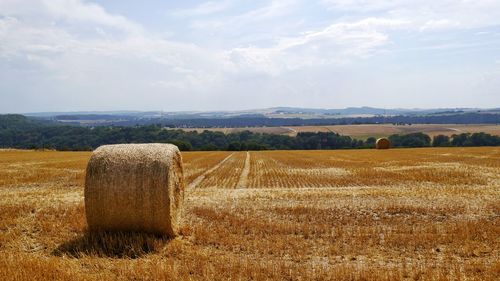 Hay bales on field against sky