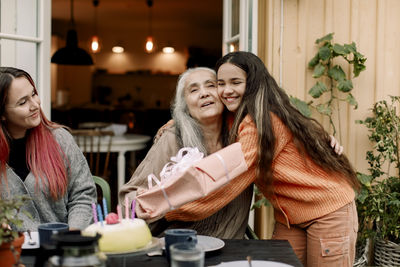 Happy girl embracing and wishing grandmother on birthday at patio