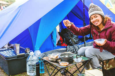 Portrait of young woman eating at campsite