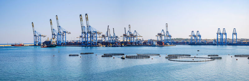 Cranes at commercial dock against clear sky