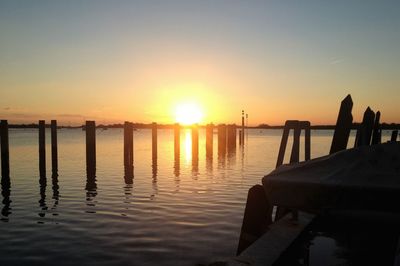 Silhouette pier over lake against sky during sunset