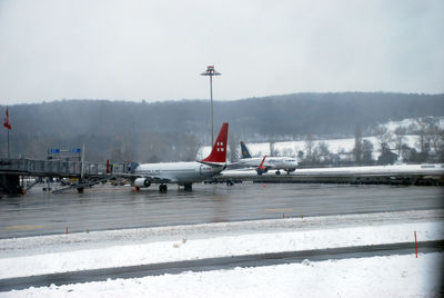 Airplane on snow covered airport runway against sky