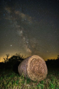 Hay bales on field against sky at night