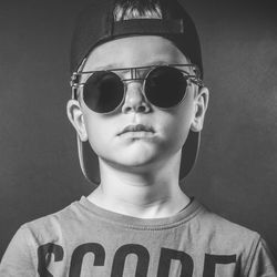 Portrait of young man wearing sunglasses against black background