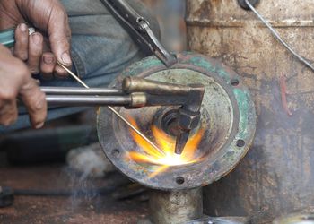 Cropped hands of welder welding metal in workshop