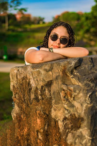 Portrait of young woman wearing sunglasses on rock