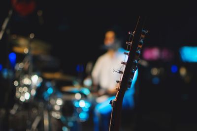 Close-up of fretboard against musician performing on stage