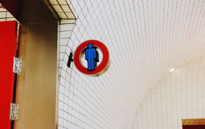 Low angle view of sign on white tiled wall