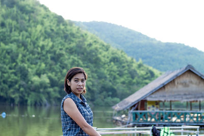 Portrait of woman standing against railing by lake