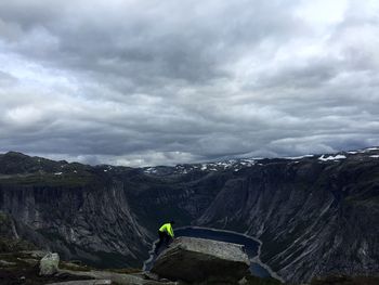 Man standing on rock against sky