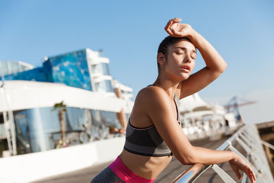 Woman leaning on railing against sky