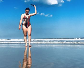 Full length of woman standing on beach against sky