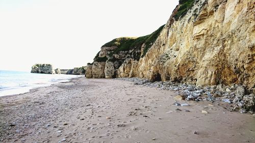 Rock formations on beach against clear sky