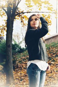 Portrait of smiling young woman standing in park during autumn