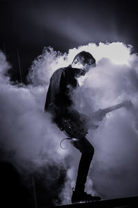 Man playing guitar in concert at night