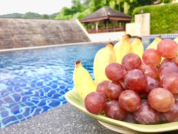 High angle view of grapes in container on table by swimming pool