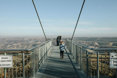 Rear view of woman on bridge against sky