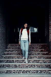 Portrait of smiling young woman standing against wall