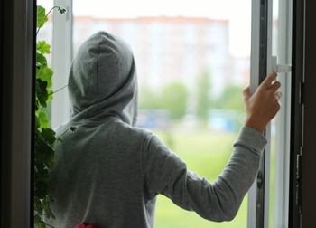 Rear view of man looking through window