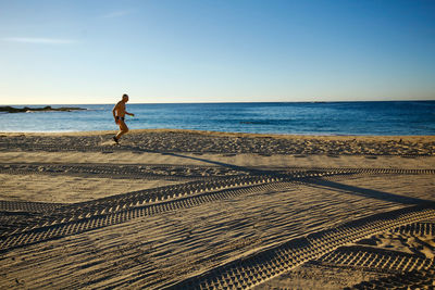 Full length of man on beach against clear sky