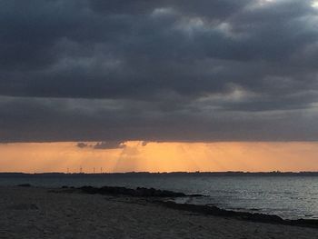 Scenic view of sea against dramatic sky during sunset