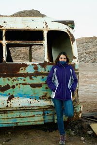 Full length portrait of woman standing against abandoned building