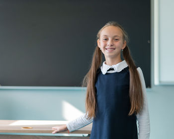 Portrait of young woman standing against wall