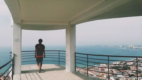 Rear view of man looking towards while sea walking at observation in city