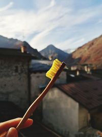Close-up of hand holding ice cream against sky