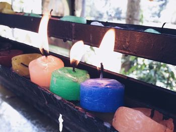 Close-up of multi colored tea light candles on railing