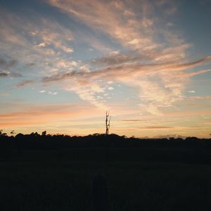 Silhouette of electricity pylon against dramatic sky