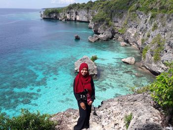 Portrait of man standing on rock by sea