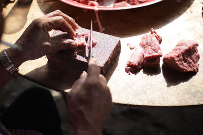 Close-up of hand holding meat on cutting board