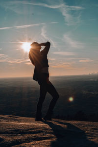 Man standing on sea shore against sunset sky