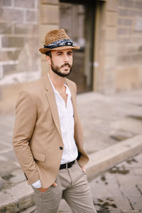 Man wearing hat looking away while standing outdoors