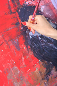 Midsection of woman holding red paint