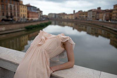 Woman bending over backwards on bridge in city