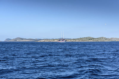 Sailboat sailing on sea against clear blue sky