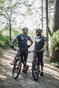 Male cyclist talking to each other while standing with cycles on footpath