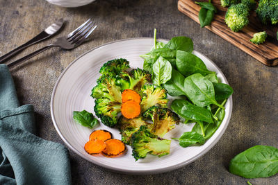 Grilled broccoli and carrots and fresh spinach leaves on a plate. vegetable diet.