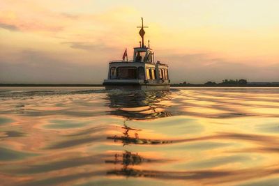 Surface level view of boat on lake at sunset