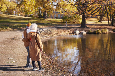 Rear view of woman standing by lake