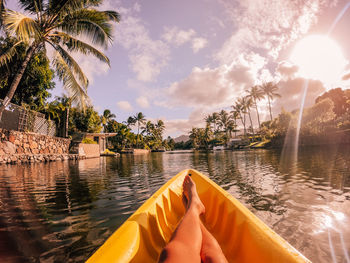 Low section of woman relaxing on boat in river against sky