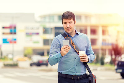 Young man using phone while standing on street