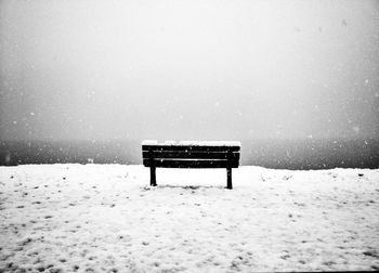 Empty bench on snow covered field